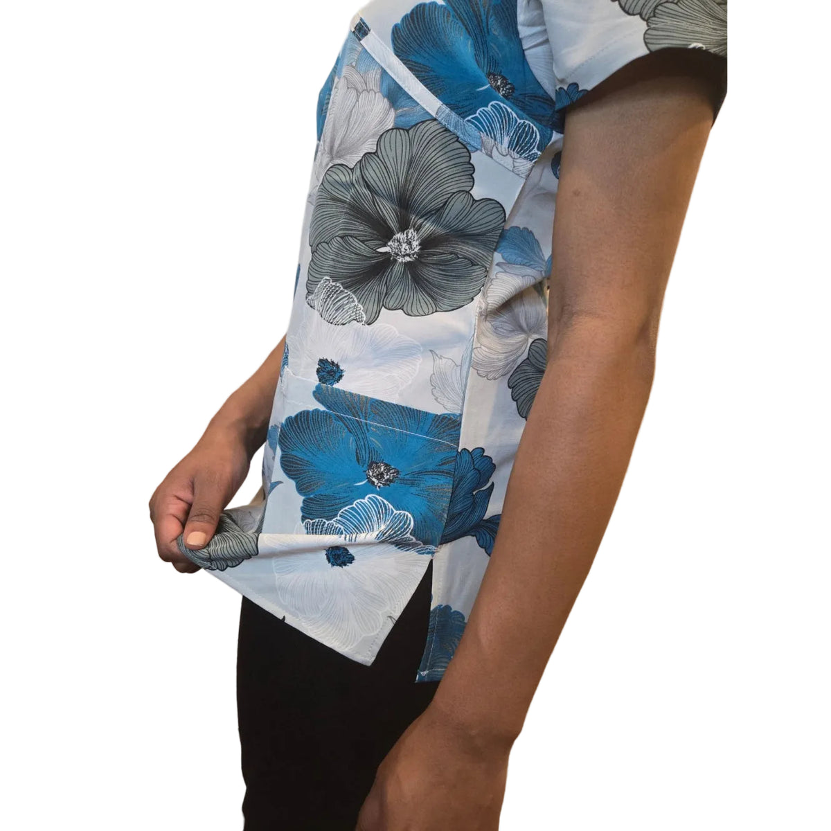 A close-up of a person's arm and hand holding up a white shirt with a large blue and gray floral print, showing the fabric texture and pattern details.