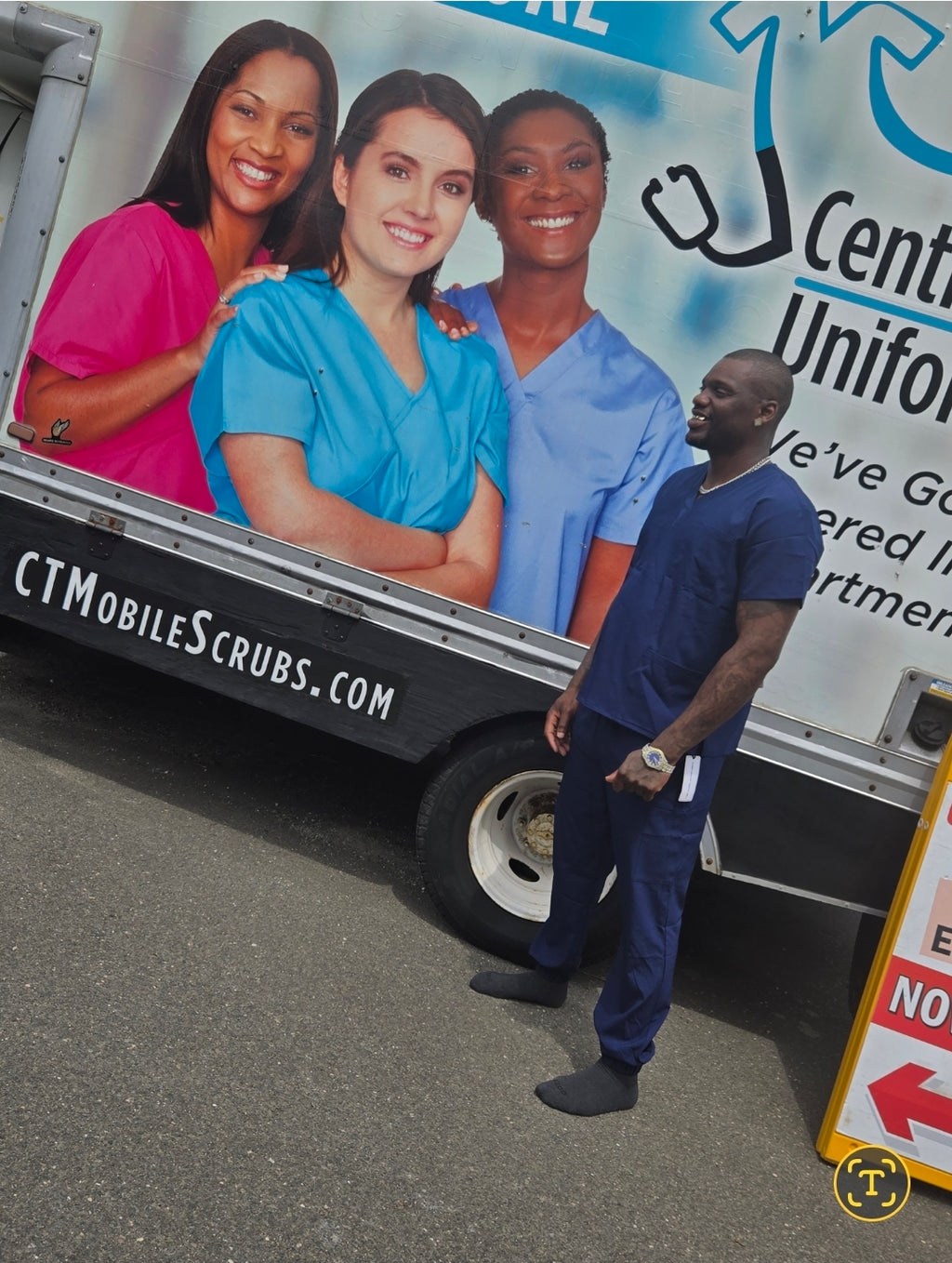 Man in scrubs standing next to a truck with promotional images of people wearing scrubs.
